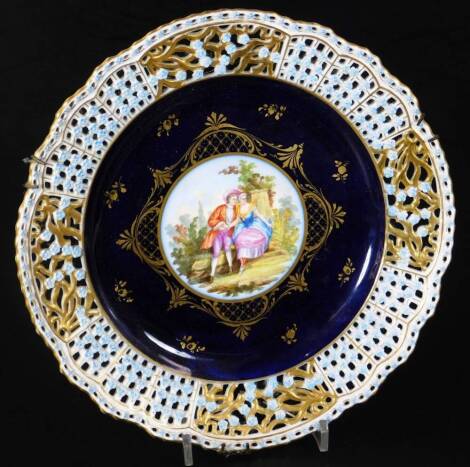 A Meissen porcelain plate, with pierced rim broken by flowers, with gilt highlights, the centre set with a partially hand painted portrait of two figures in a garden setting, on a powder blue and gilt ground, impressed marks beneath, 26cm wide.