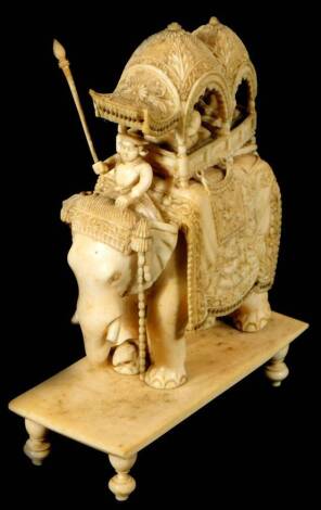 An early 20thC Indian ivory carving of an elephant and mahout, with two figures in attendance on a platform base, 15cm H.