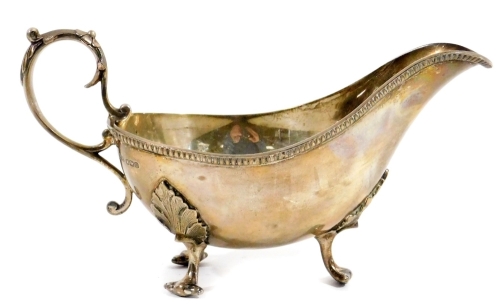 An Edwardian silver sauce boat, of cape form, with a repeat geometric banding, acanthus capped S scroll handle and triple acanthus leaf hairy paw feet, Sheffield 1904, 10cm H, 8oz.