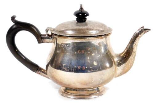 A George V silver bachelor's teapot, of bellied circular form, with compressed domed lid, ebonised knop and thumb mould handle, on circular foot, London 1919, 14cm H, 10oz.