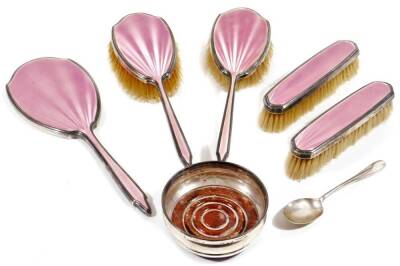 A George VI silver and pink enamel dressing table set, comprising of hairbrush, 24cm W, another, two clothes brushes and hand mirror, London 1935, a coaster and a silver spoon. (a quantity)