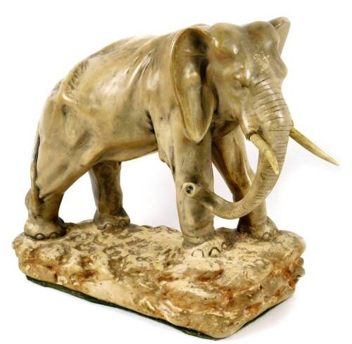 An early 20thC pottery figure of an elephant, on a rock work base, with trunk lowered, baize lined, numbered to the back, 40cm H.