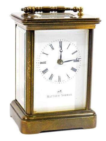 A 20thC Matthew Norman carriage clock, in brass case with swing handle, raised above a five part glazed section, with 5.5cm Roman numeric dial, on bracket feet, single train keywind movement, 13cm H. (with key)