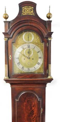 Kenneth Maclennan, London. A late 18thC mahogany and flame mahogany longcase clock, the shaped hood with a blind fret flanked by orb finials, above partially gilt highlighted columns and an arched long flame mahogany trunk door, above a further flame mah