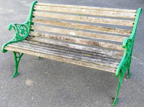 A wooden slatted cast iron garden bench, with pierced iron scroll and floral ends and shaped feet, 78cm H, 127cm W, 65cm D.