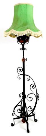 A wrought iron standard lamp, with cylindrical stem and scroll legs, with green shade, 145cm H.