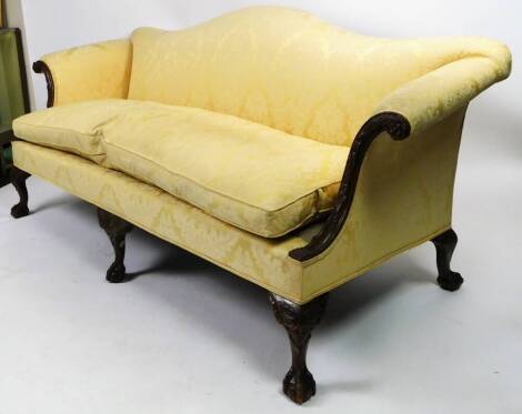 A George III style serpentine backed salon settee, with heavily carved scroll arms and squat cabriole legs, terminating in claw and ball feet, upholstered in floral material, in the manner of Waring and Gillow, 95cm H, 209cm W, 96cm D.