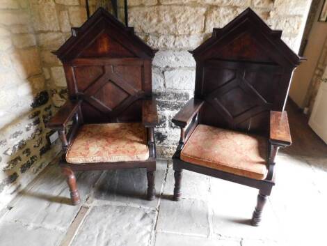A pair of ecclesiastical type bishop's oak throne chairs, each with carved triangular tops, panelled backs and block arms, on turned baluster front legs, 154cm H. (2)