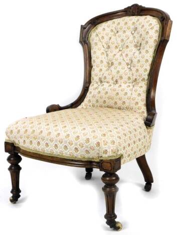 A late Victorian walnut open armchair, with button back and shaped seat, in floral material, on turned front legs terminating in castors, 90cm H.