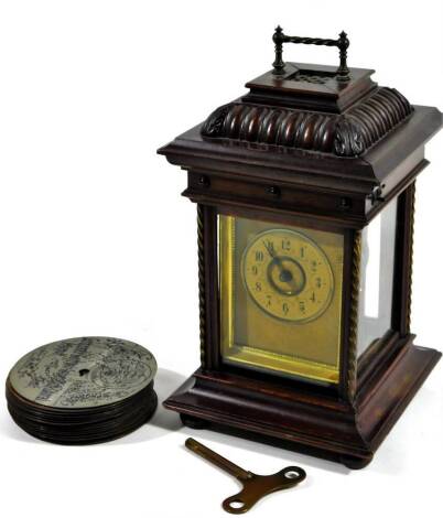 A Edwardian walnut mantel clock disc symphonium, with park gadrooned square top above a four part glazed case, on shaped base with 8cm dia. Arabic dial and disc playing feature, various symphonium 12cm Dia. discs, 28cm H.