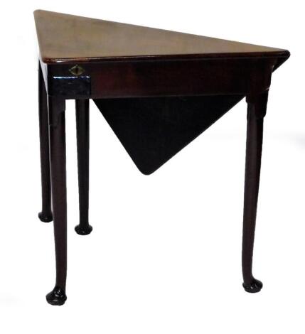 A George III mahogany triangular topped gateleg table, with lidded top revealing a shallow well, raised on cylindrical legs terminating in pad feet, when closed 70cm H, 82cm W, 45cm D.