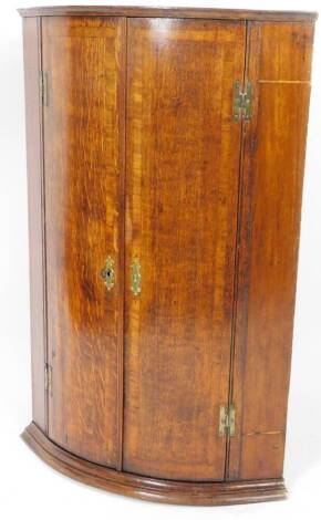 An 18thC oak hanging corner cabinet, of barrel form, with a fitted interior, 96cm H, 67cm W, 43cm D.