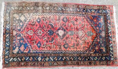 A Turkish rug, with a design of medallions in navy, on a red ground with blue spandrels, one wide and two narrow borders (AF), 79cm x 102cm.