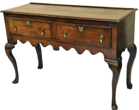 A late 18thC oak dresser base, with moulded top, two crossbanded frieze drawers with pear drop handles, shaped apron and cabriole legs with pointed toes on pad feet, 84cm H, 127cm W, 52cm D.