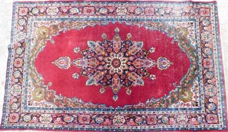 A Persian rug, of rectangular form, in floral pattern predominately in orange, blue and green, 162cm x 98cm.