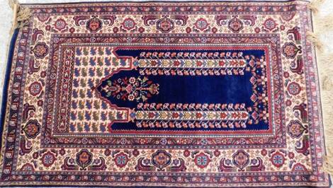 A Middle Eastern prayer rug, of rectangular form, decorated with flowers in a geometric pattern predominately in red, cream and blue, 155cm x 93cm.