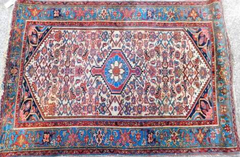 A rug, of rectangular form, decorated with geometric pattern and flowers predominately in red and blue, 150cm x 104cm.