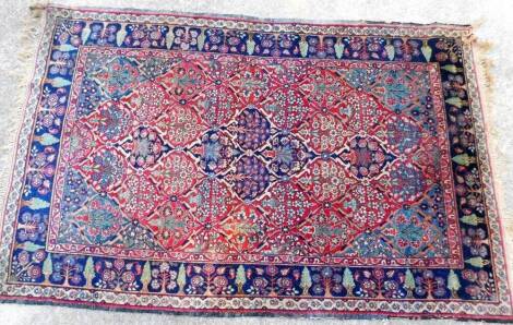 A Persian rug, of rectangular form, decorated with trees, flowers, predominately in blue, red and cream, 200cm x 127cm.