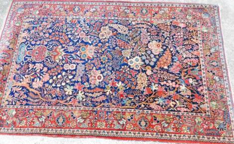 A Persian rug, of rectangular form, decorated with birds, flowers and a geometric pattern, predominately in red, blue and green, 215cm x 135cm.