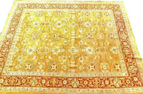 A 20thC woollen carpet, in a repeat geometric pattern, set with diamonds and flowerheads, predominately in orange, brown and yellow, 354cm x 270cm.