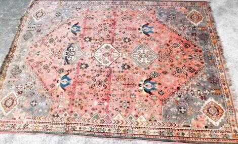 An early 20thC hand knotted carpet, of rectangular outline, probably Middle Eastern, decorated with geometric and floral patterns predominately in grey, orange and turquoise, 280cm x 200cm.