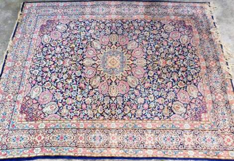 An early 20thC Persian rug, of rectangular form, decorated with flowers, predominately in blue, pink and green, with outer geometric banding, 335cm x 260cm.