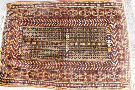 An early 20thC Middle Eastern hand knotted rug, of rectangular form, with tasselled end, decorated with a geometric floral pattern, predominately in orange, red and black, 130cm x 87cm.