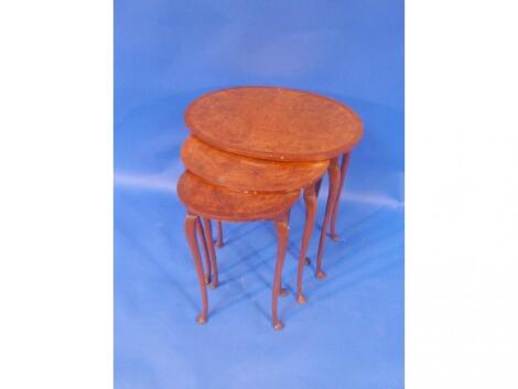 A burr walnut nest of three tables each cross banded and quarter veneered