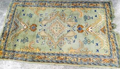 An early 20thC woollen hand knotted rug, probably Middle Eastern, decorated with flowers, predominately in green and blue, 206cm x 124cm.