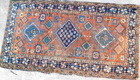 A early 20thC Middle Eastern rug, with a diamond centre and floral surround, possibly Afghanistan, predominately in blue, pink and orange. 180cm x 96cm.