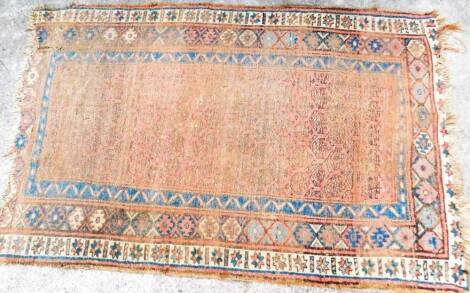 An early 20thC hand knotted rug, of rectangular form, with an outer geometric floral pattern and similar inner decoration, predominately in orange, blue and cream, 215cm x 137cm.