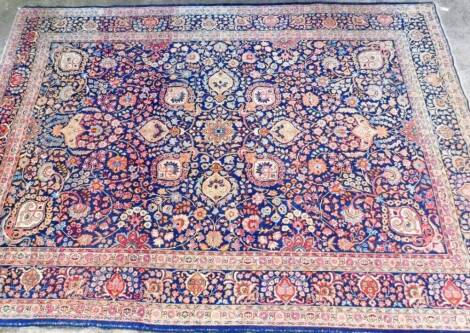 A large 20thC hand knotted carpet, of rectangular form, decorated with flowers and geometric pattern, probably Persian, predominately in blue, yellow, orange and cream, 350cm x 248cm.