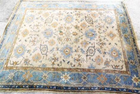 A late 19thC Maples Middle Eastern design hand knotted rug, predominately in blue, green and orange, on a fawn ground, 390cm x 312cm.