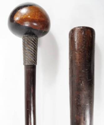 An African tribal hardwood knobkerrie, with compressed orb top and cylindrical stem broken by a turned grip, with strung end, 67cm W, and a hardwood coch. (2) - 2