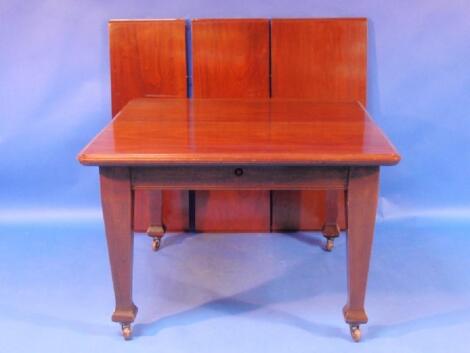 An Edwardian mahogany extending dining table on square taper legs with