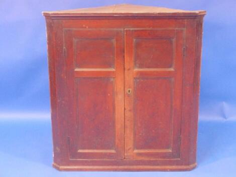 A George III pine hanging corner cupboard with two panel doors