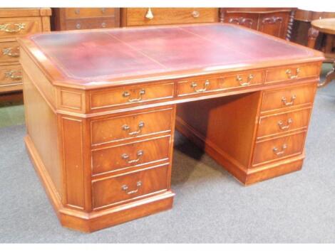 A reproduction flamed mahogany partners desk with canted top