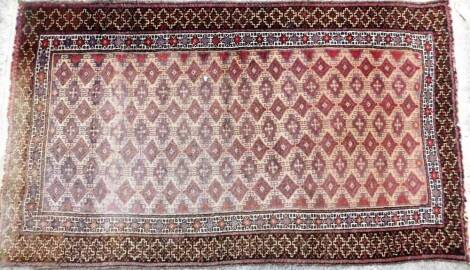 An early 20thC hand knotted rug, of rectangular form, with a diamond and geometric design, predominately in purple, red and fawn, 150cm x 86cm.