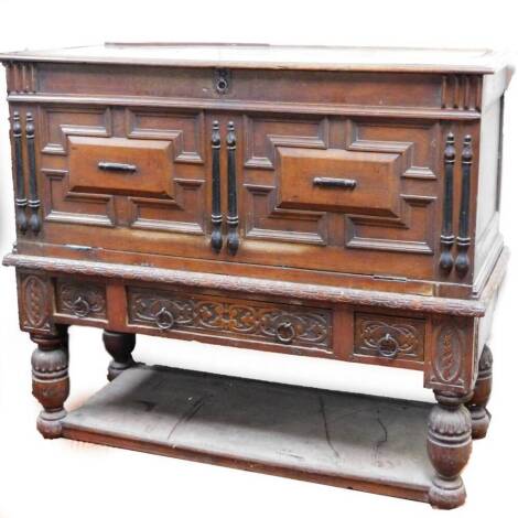 A 19thC continental oak side cabinet, the heavily carved front with inverted panelled fall, raised above three drawers, on heavy legs joined by a shelf, partially carved with flowers and scrolls, 111cm H, 136cm W, 53cm D. (AF)