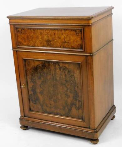 A Continental walnut veneered gentleman's washstand, the rounded top hinging with fitted interior, with a panelled front with single cupboard, on compressed bun feet, the top with a wide crossbanding, 98cm H, 72cm W, 48cm D.