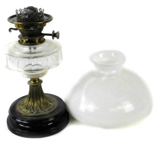 A Victorian brass oil lamp, with later opaque shade, clear faceted glass reservoir and tapering base with black ceramic plinth, 50cm H.