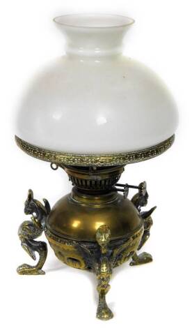 A 19thC brass oil lamp, with later opaque shade, the base applied with three winged griffin type figures, 35cm H.