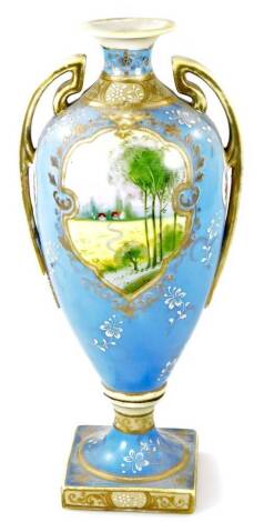 A Noritake porcelain two handled pedestal vase, handpainted with reserves of landscape decoration on a lavender blue ground, 29cm H.