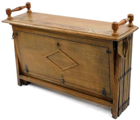 An early 20thC oak campaign bed, of rectangular form with concertina action, turned handles and block stiles, 70cm H, 100cm W, 28cm D.