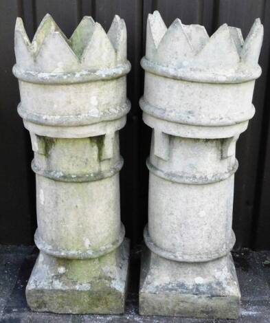 Two chimney pots, of cylindrical form, with castellated tops on square bases, 90cm H.