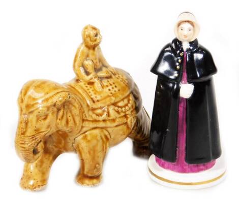 A late 19thC treacle glazed money box, in the form of an elephant, with a monkey on its back, 12cm H, and a Crown Derby candle snuffer, Ste[phenson & Hancock 1861 - 1865, formed as a lady in a black cloak. (2)