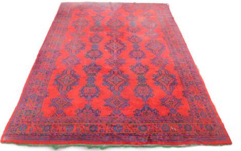 A Persian style red ground rug, decorated with repeating geometric medallions in five rows, within a floral border, 510cm x 390cm.