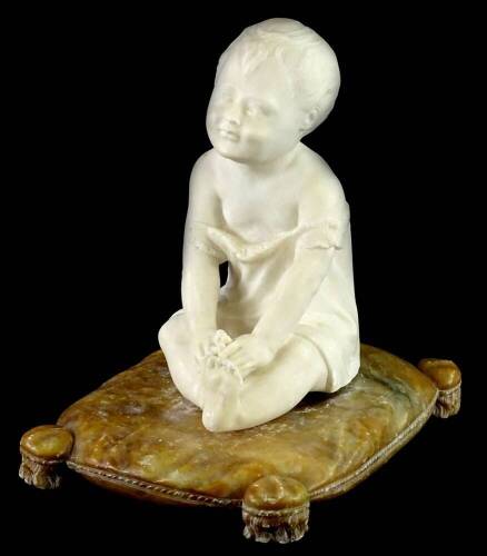 A continental marble and alabaster sculpture, carved in the form of a young child seated on a tasselled cushion, unsigned, 27cm H, 17cm W.