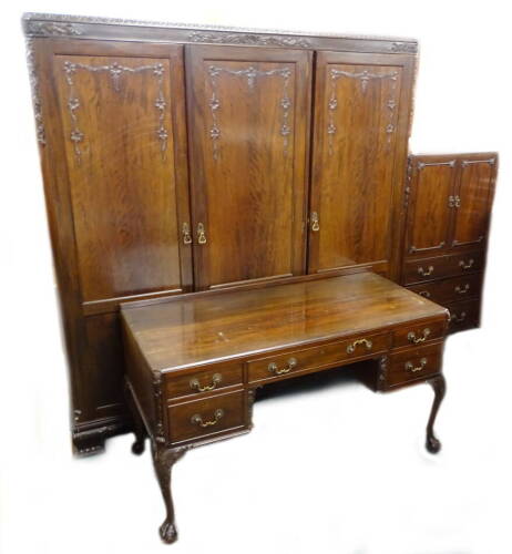 A Heal and Sons mahogany bedroom suite, in Chippendale style, comprising three door wardrobe on carved ogee bracket feet, a similar small cupboard or tall boy with two panel doors and three drawers, and a dressing table on cabriole legs with five drawers.