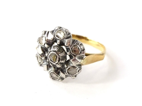 A diamond cluster ring, set with seven rose cut diamonds, totalling approx 0.27cts, beaded setting in white onto open work textured mount, yellow metal, marked, rubbed, tests as 18ct gold, setting tests as sterling silver, ring size R½, 7.24g all in. Wi